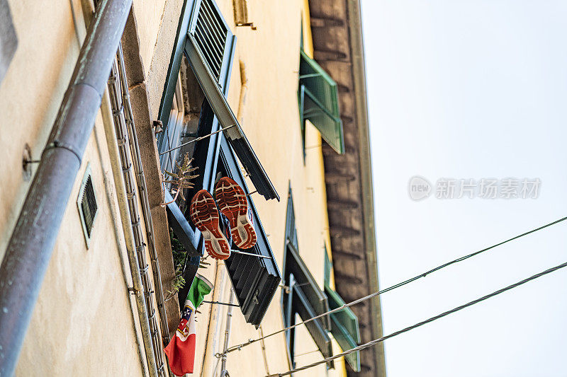 比萨小巷的原始视角。鞋和意大利国旗挂在窗户上，意大利