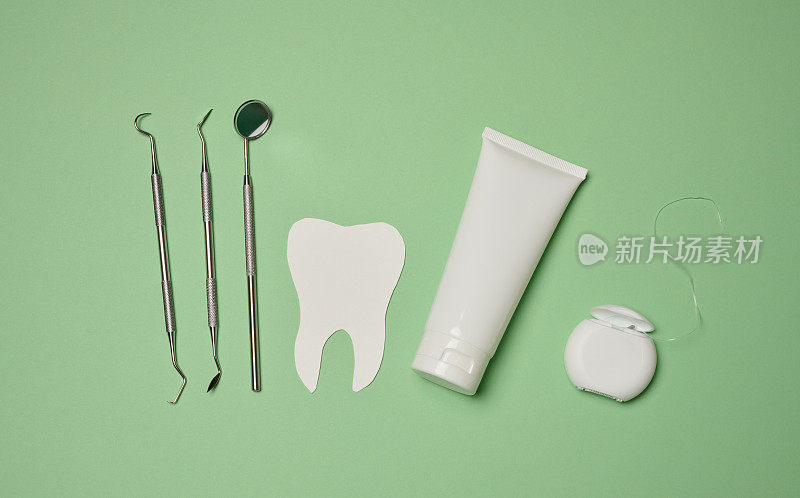 管内装有牙膏、牙线和医用镜，绿色背景，口腔卫生。