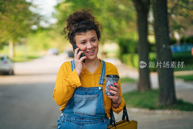 一个轻松的卷发女人一边走一边打电话。