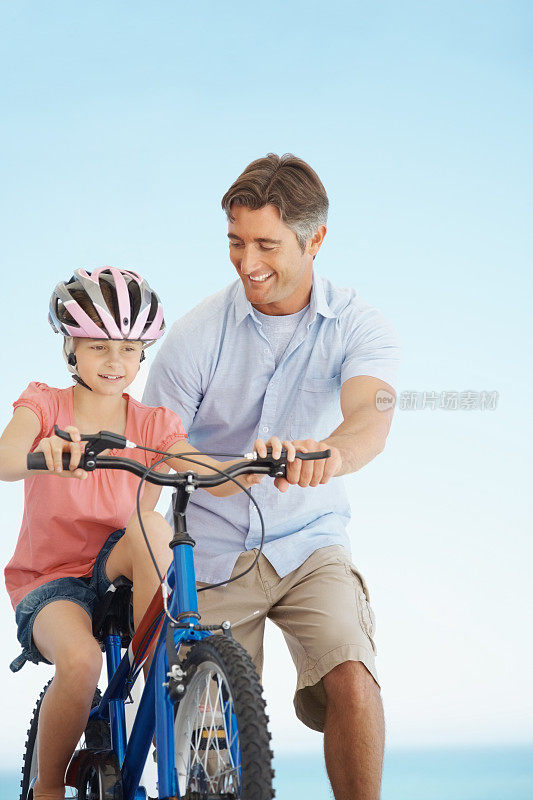 一个男人帮他的女儿骑自行车