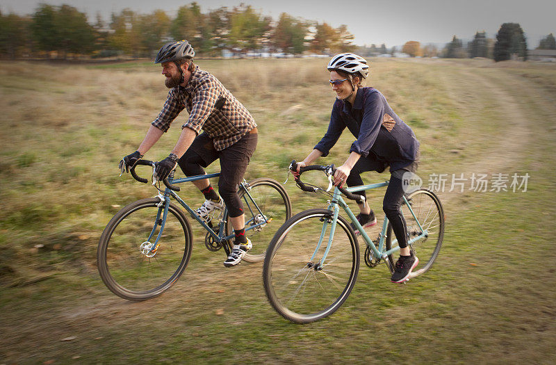 男人和女人骑着他们的自行车穿过一片田野
