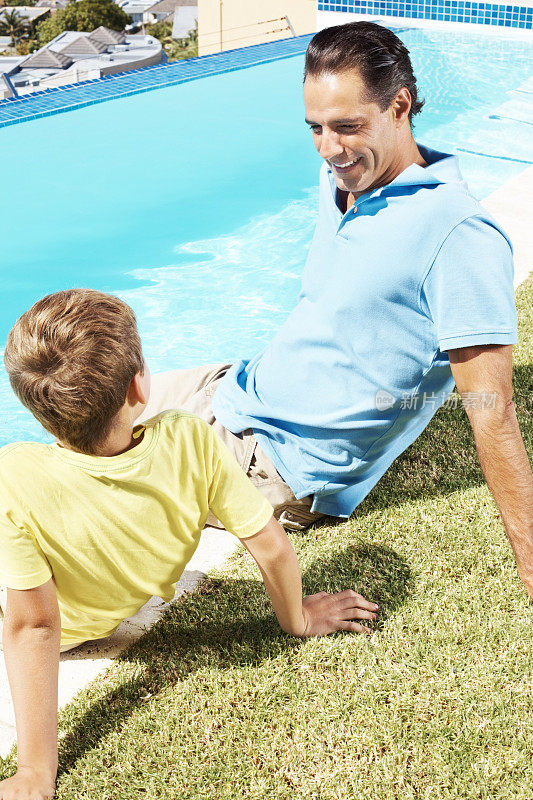 快乐的男人和他的小儿子坐在水池旁