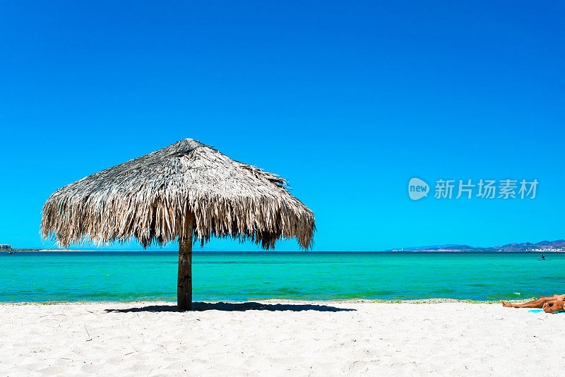 白色的沙子，清澈的绿松石水和一把棕榈太阳伞