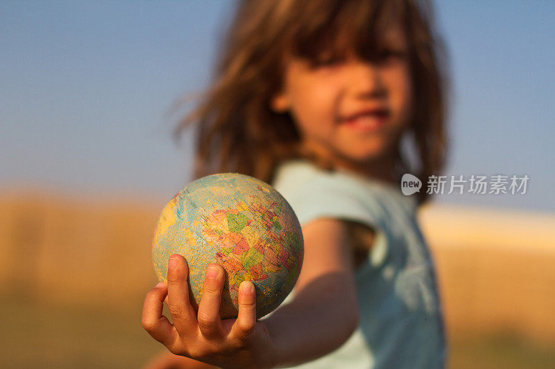 孩子手里拿着一个地球仪玩具