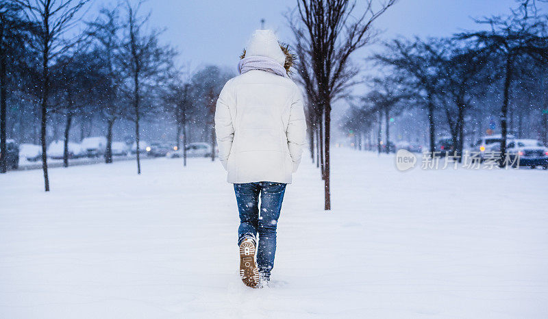 雪下穿着白色夹克的漂亮少女