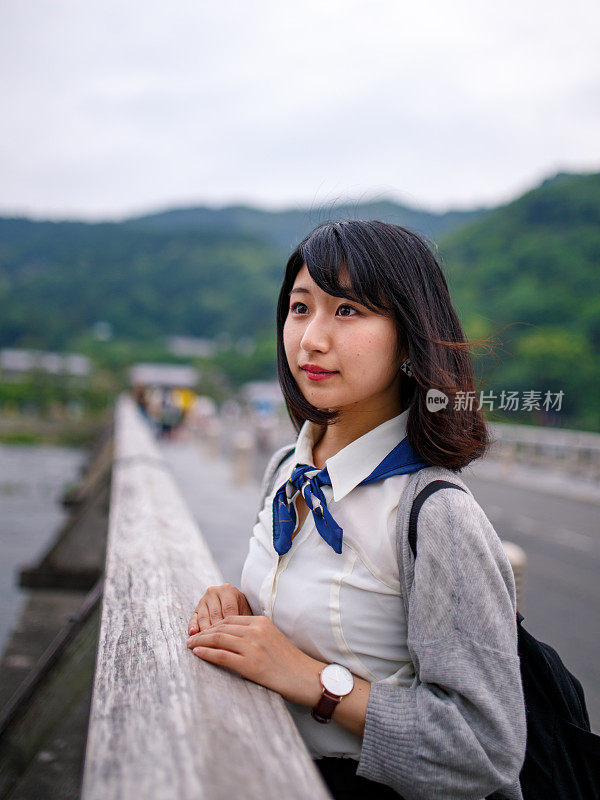 年轻的日本女孩从桥上看风景