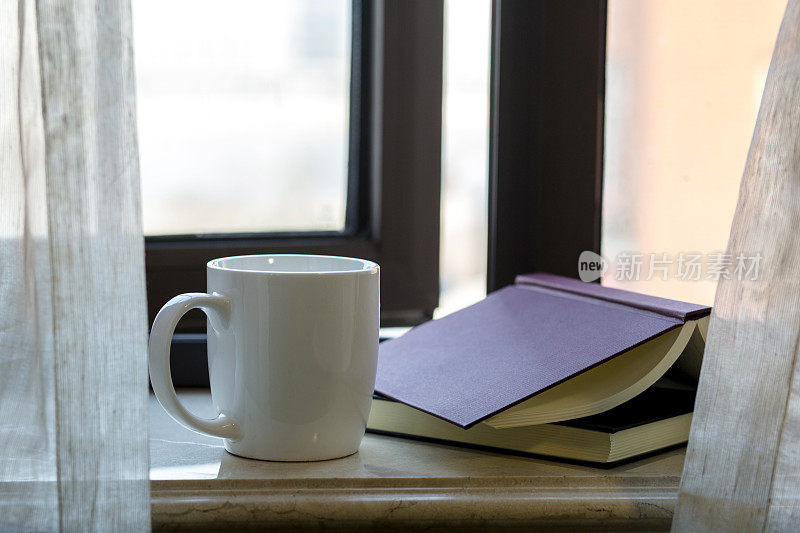 窗台上放着书和咖啡杯