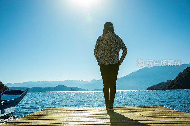 站在湖边码头上的女人