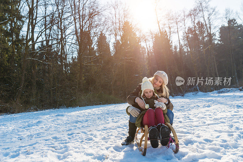 妈妈和女儿玩雪橇玩得很开心