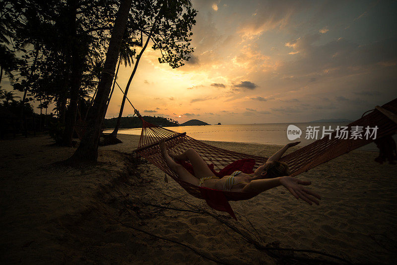 躺在吊床上的女人，热带海滩上的夕阳