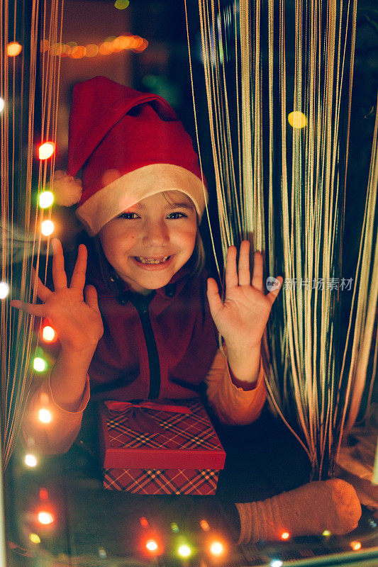 快乐的孩子在圣诞老人的帽子里打开圣诞礼盒