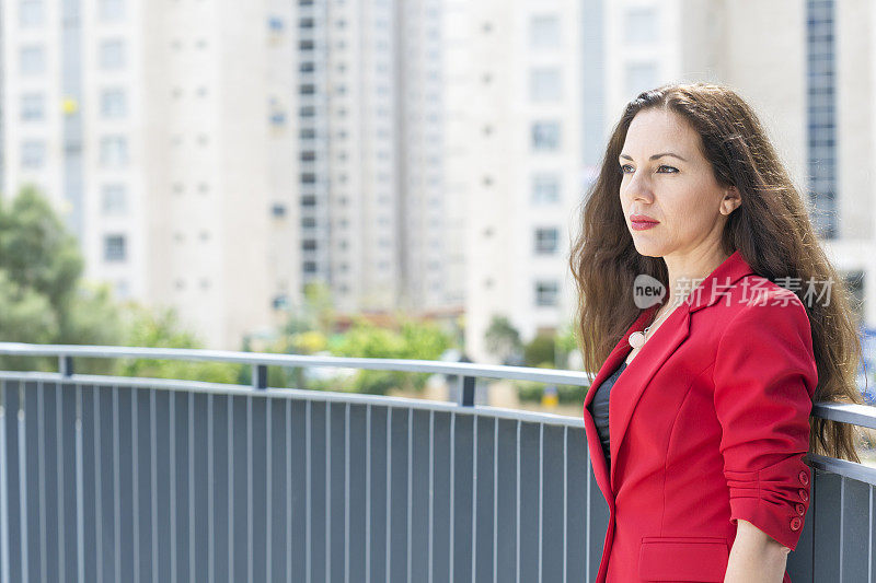 穿着红夹克的时髦女人站在桥上