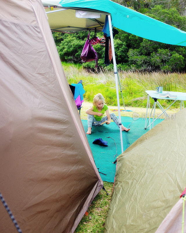 小女孩在夏令营的帐篷外读书