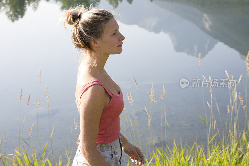 年轻女子沿着山湖边散步