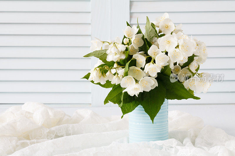 木质背景上的花瓶里放着新鲜的茉莉花