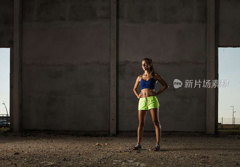 全长女运动员站在废弃的仓库。