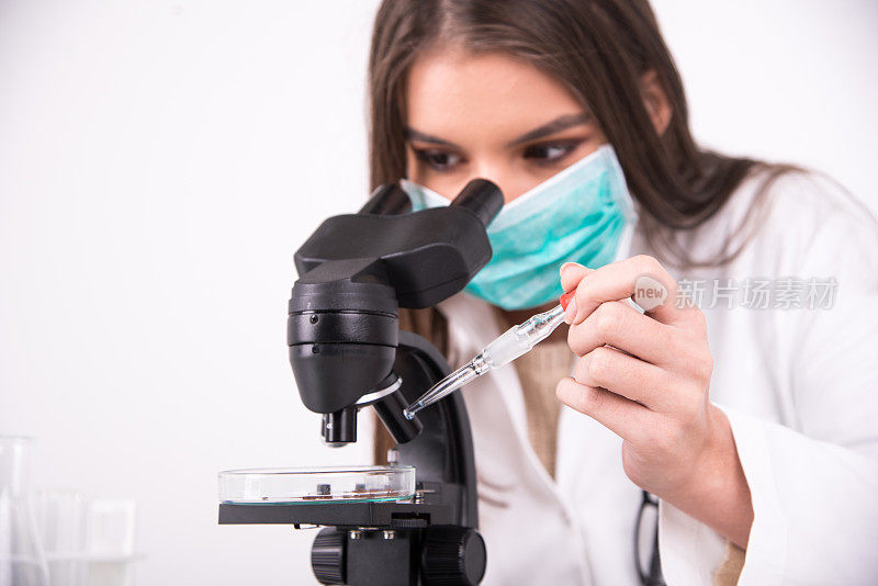 一位女科学家通过显微镜观察的特写镜头