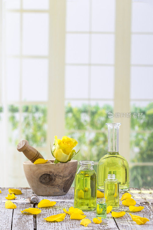 窗户背景上的黄玫瑰花，木臼上的草药