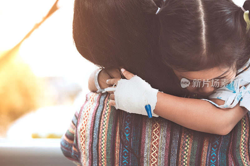 生病的小女孩在医院里拥抱和依靠在她母亲的肩膀上