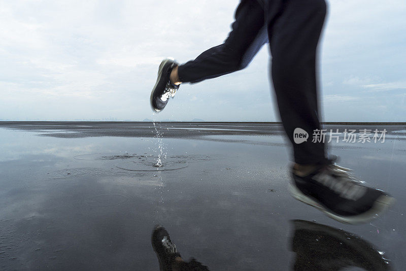 照片中的男运动员跑过水坑对着多云的天空