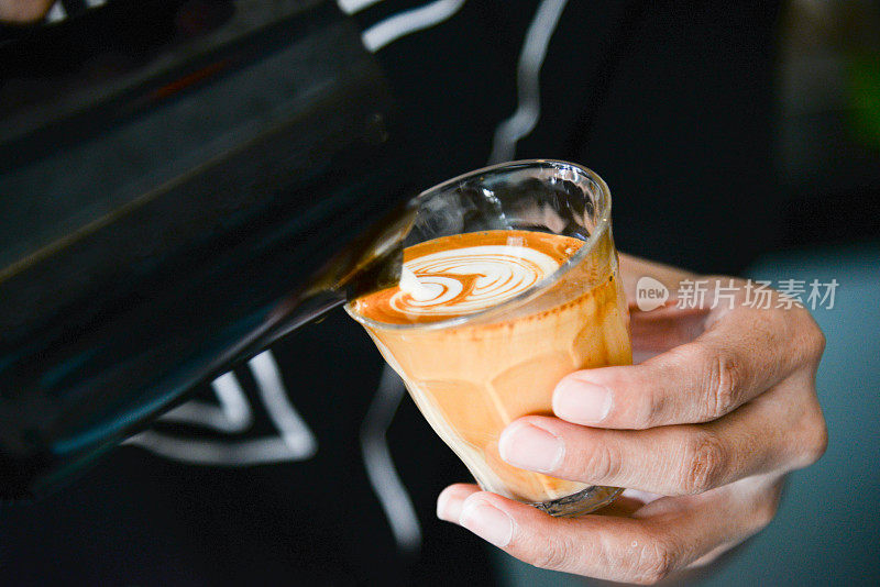 咖啡师制作的拿铁艺术专注于牛奶和咖啡。咖啡师的手倒牛奶制作拉花艺术