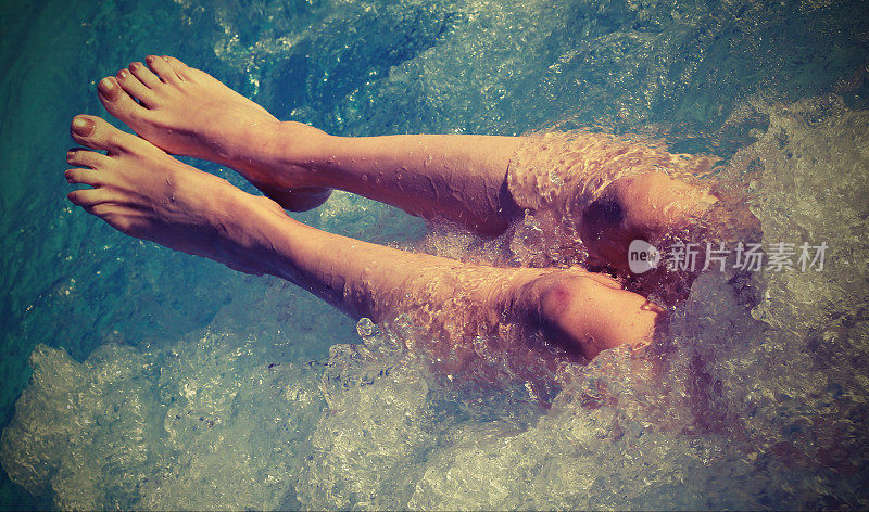 一个年轻女子在游泳池里按摩时的光脚