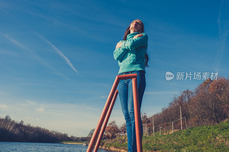 年轻女子躺在湖边的码头上，披着毯子，看日落