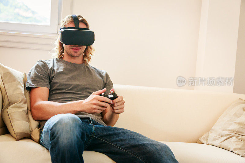 年轻人坐在沙发上，戴着VR眼镜