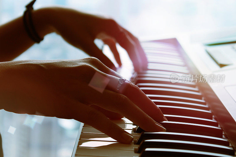 弹奏键盘近景的钢琴前景和柔和的光线。
