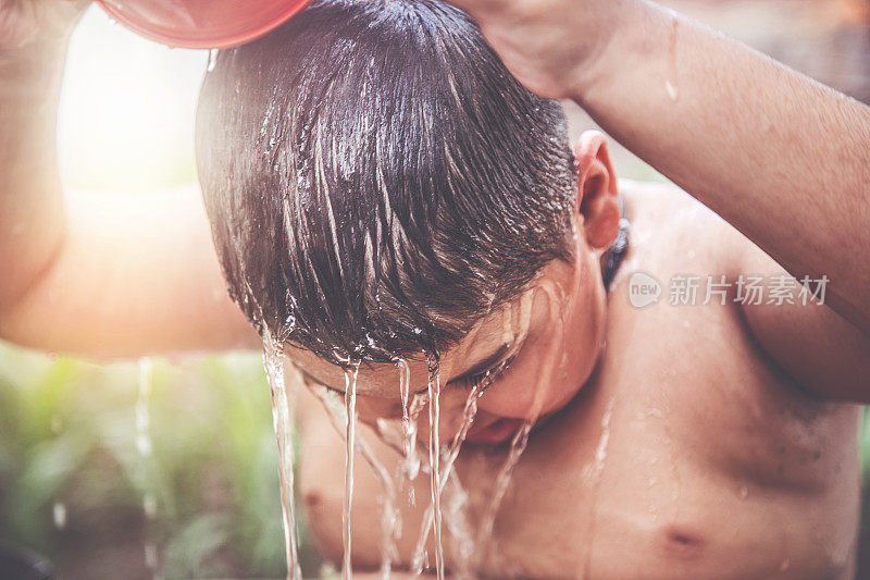 一个年轻的印度男孩在水龙头下洗澡