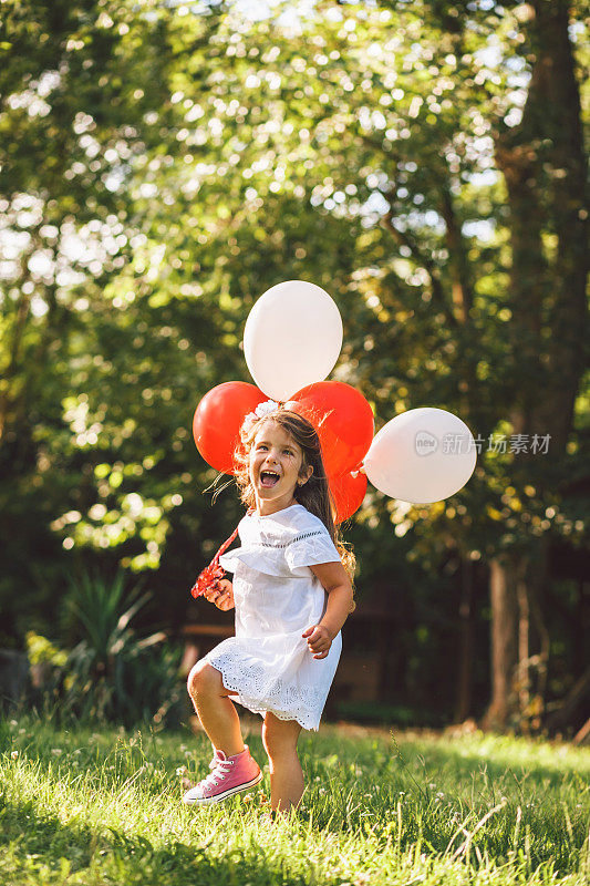 快乐快乐的小女孩与气球在草地上