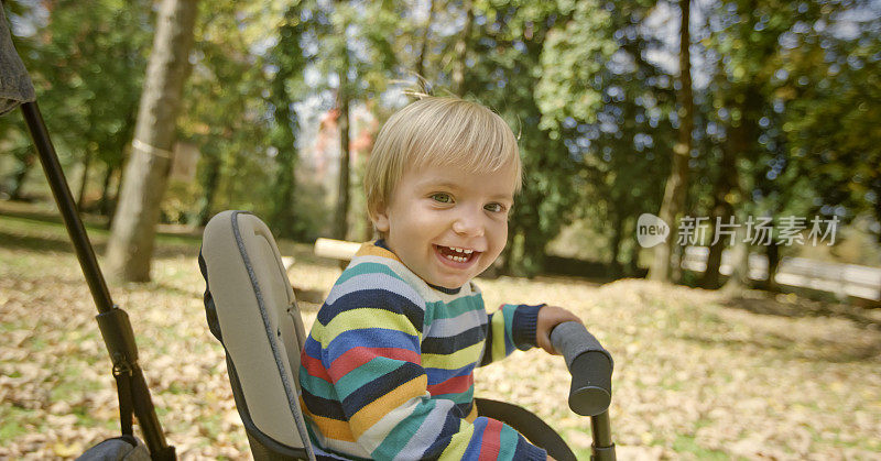 微笑的小男孩坐在三轮车上