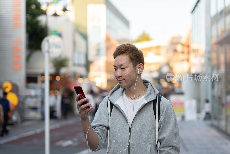 年轻人在街上用智能手机听音乐