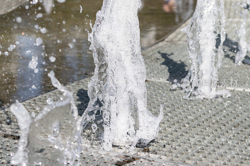 流动的城市喷泉的水飞溅，泡沫的喷射。城市公园的休闲区碎片
