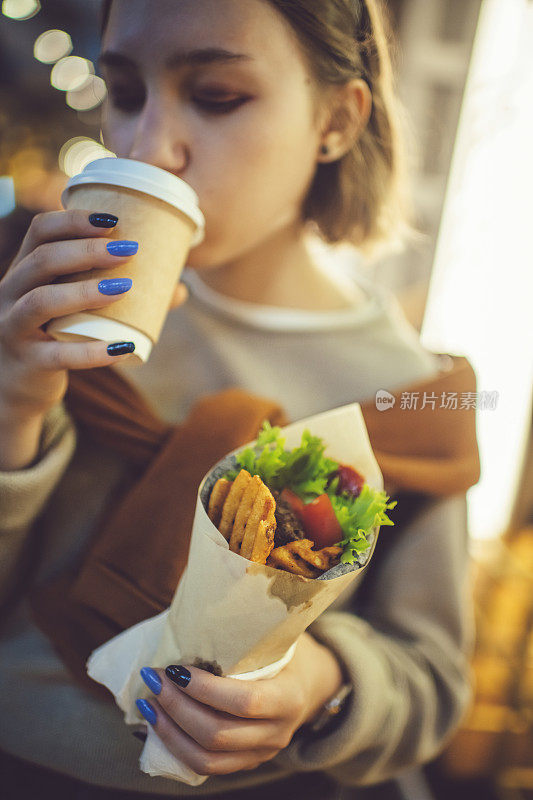 快乐的少女喝咖啡和街头小吃在晚上的城市在夏天