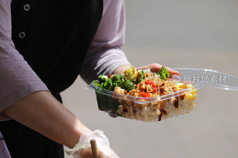 在户外烧烤街食品市场健康地吃什锦饭沙拉，食物装在塑料饭盒里，配有一次性食品卫生手套、冷白米、甜玉米、炒鸡、洋葱、辣椒、花椰菜