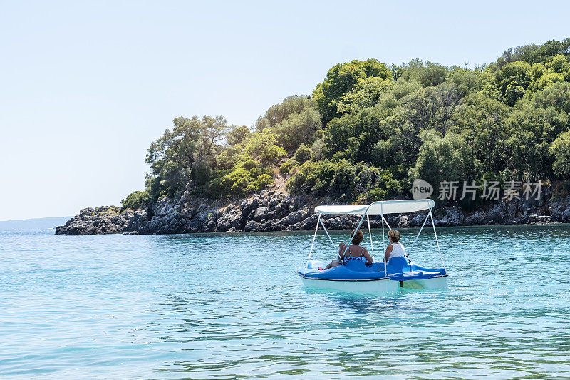 两个年长的女人在海上的一艘脚踏船上休息