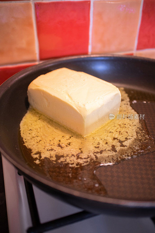 一大块黄油在热锅中融化，准备制作面包和黄油布丁