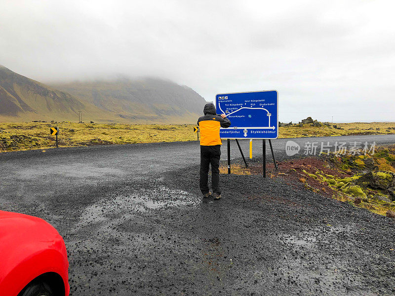 冰岛公路旅行:男人在雨中在路边拍摄地图