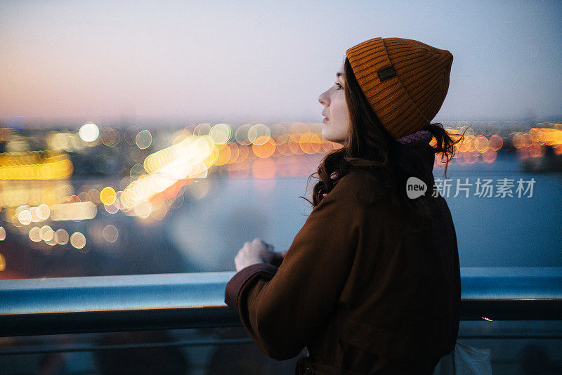 一名女子站在人行天桥上，欣赏基辅美丽的城市风光