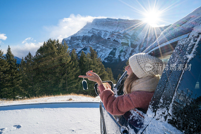 一名年轻女子在冬天在加拿大的雪山路上租了一辆车