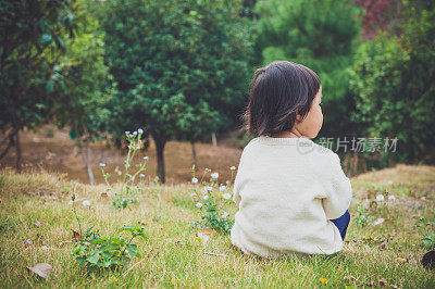 一个中国女孩坐在花园里的草地上