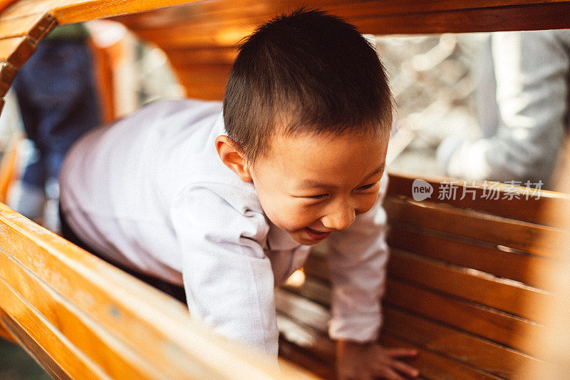 可爱的亚洲幼童有乐趣尝试爬上一个方格架