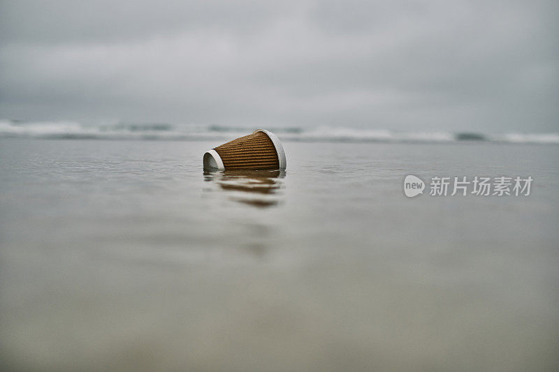 环境问题，被冲上岸的一次性塑料杯在海滩的海岸线。