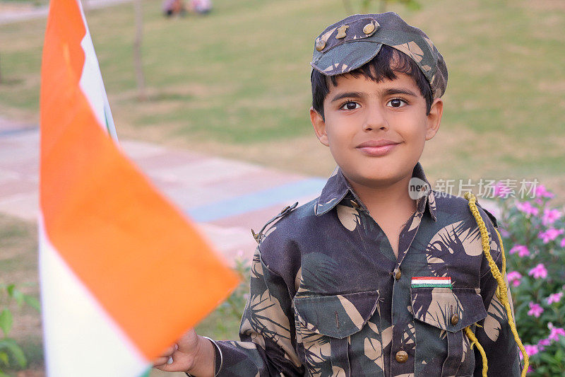 小学生手持旗帜，身穿军装，在户外拍摄独立日庆祝活动肖像。