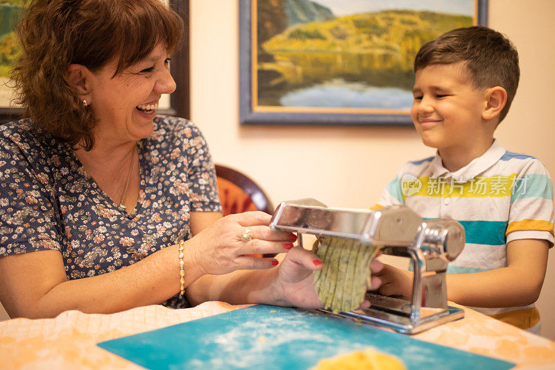 一个可爱的男孩和他的奶奶用意大利面机做意大利面