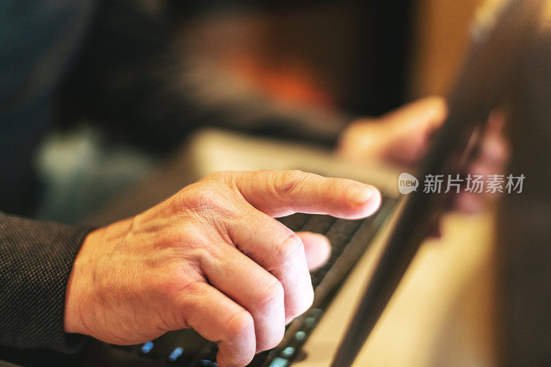 成熟的成年男性的手在笔记本电脑技术键盘上敲击玻璃桌面从主图像工作