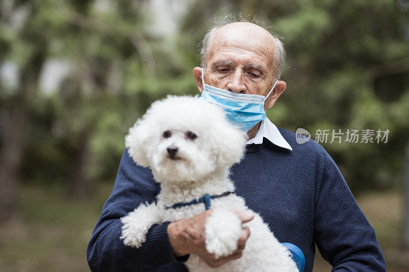 一名男子手里抱着一只卷毛比熊犬