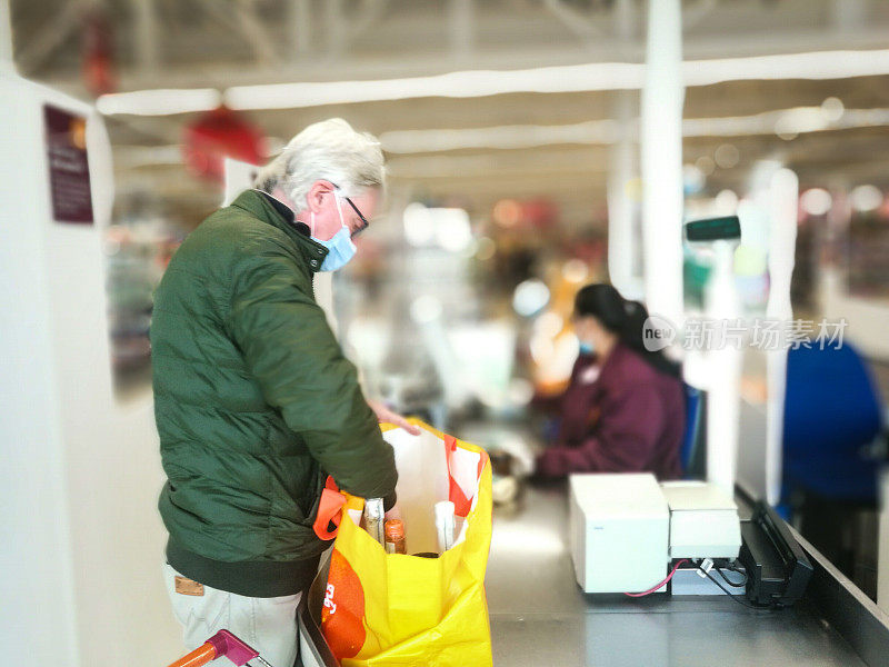 戴着防护口罩的老人在超市结账处