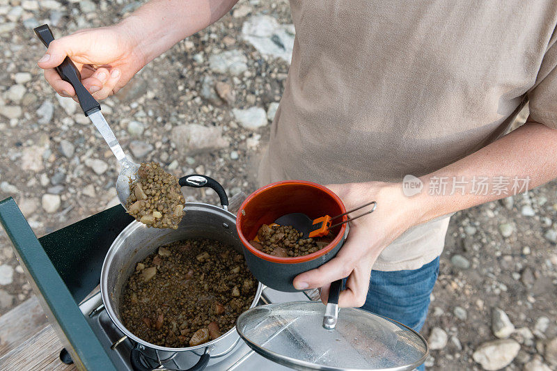 科罗拉多州的素食者用野营炉舀扁豆进碗里